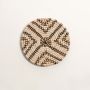 Round woven wall plate with geometric black and beige design placed on white background for modern wall styling.