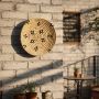 Handcrafted round wall decor in natural fiber mounted on brick wall adding warm rustic texture and artistic charm to outdoor seating area.
