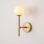 Gold wall light with non illuminated white globe displayed on a white background showcasing the clean structure and modern vertical metal rod design.