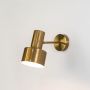 A gold wall light with a cylindrical adjustable head shown switched on against a clean white background casting a warm focused glow downward.