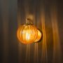 Modern amber glass wall light with brass fixture glowing warmly against black background interior.