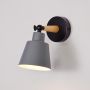 Grey metal wall light switched on with black base and wooden arm on white background delivering warm illumination for indoor wall use.