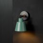 Contemporary wooden wall sconce with green conical lampshade glowing warm light on black background for bedroom study and hallway stylish wall decor.