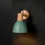 Wall light glowing with matte green shade wooden base and black cord creating soft ambient illumination for modern interiors.