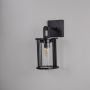 Black metal lantern wall light with cylindrical glass shade and exposed bulb shown off on white background for home decor.