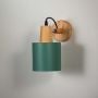 Wall sconce with matte dark green cylindrical shade wooden base and black cord perfect for bedroom living room and hallway walls.