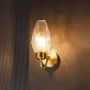 Wall light glowing with geometric clear glass shade and gold finish base creating soft ambient illumination for stylish interiors.
