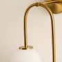 Close view of golden wall light with white glass globe showing refined detailing and sleek craftsmanship.