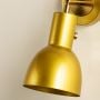 A closeup of a gold metal wall light presented against a smooth beige wall showing its rich metallic surface and adding luxurious modern sconce décor.