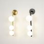 Set of modern gold and black wall sconces with three glowing frosted glass globes displayed together on plain white background view.