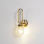 Modern gold wall sconce with loop frame and textured glass shade glowing softly photographed on plain white background product view.