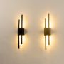 A grouped display of black linear wall sconces with illuminated acrylic tubes shown with lights on creating a cohesive warm and modern lighting setup.