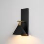 Illuminated black cone shade wall light with brass gold metal arm emitting warm ambient light on pristine white background.