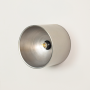 Wall light turned off on white background displaying clean cylindrical profile neutral finish and central bulb socket with modern minimal design.