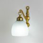 Antique brass wall light with frosted glass shade glowing warmly for living room and bedroom wall decor.