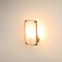 Rectangular alabaster wall sconce illuminated on white background showcasing brass detailing that adds warmth and elegance to minimalist interiors.