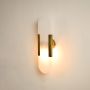 Vertical marble wall sconce illuminated on white background with golden side brackets offering warm light for hallways and living areas.