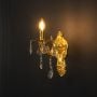 Golden wall light with crystal drops elegant candle style design displayed on light black background.
