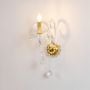 Crystal wall light with golden base and crystal drops stylish decorative wall mounted fixture on white background.