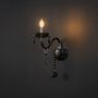Black wall light with crystal drops candle style elegant decorative fixture shown on light black background.