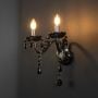 Black wall light with crystal drops and twin candle style shown on light black background decorative fixture.