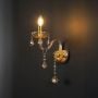 Golden wall light with crystal drops candle style elegant wall mounted lighting shown on light black background.