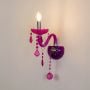 Wall light glowing with pink acrylic frame and matching crystal accents on a clean white background for vibrant decor styling.