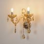 Golden crystal dual arm wall light with warm illumination ideal for bright hallway or living room wall styling.