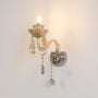 Crystal wall light with glass shade and crystal drops glowing warmly on white background for wall decor.