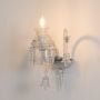 Crystal wall light glowing with detailed glass design and crystal drops on white background display.