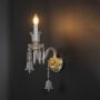 Double arm crystal wall light with detailed glass shades and crystal drops glowing on black background.