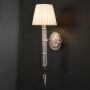 Wall light with chrome base and fabric shade glowing warmly against black background for home decor.
