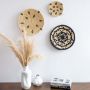 Handwoven wall basket styled on a living room wall above a wooden table with ceramic vases adding a modern rustic aesthetic.