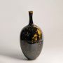 Glossy black ceramic vase with gold splatter design crafted with tall narrow neck for contemporary decor.