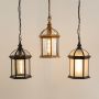 Grouped outdoor hanging lanterns with lights on displaying warm glow through clear and frosted glass panels for stylish coordinated exterior lighting.