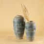 Handcrafted tall blue terracotta vase with carved motifs placed in a cozy room bringing soft artistic elegance to warm natural home styling.