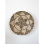 Circular woven wall hanging showcasing spiral craftsmanship and natural texture placed against a plain white background.